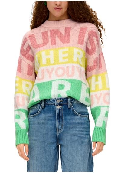 Вязаный свитер с цветной надписью по всей поверхности.