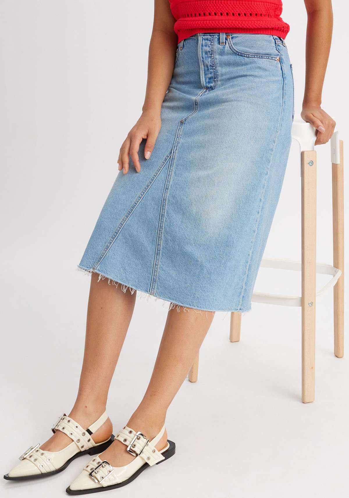 Джинсовая юбка модной длины миди с потертыми краями.