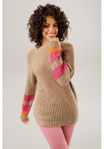Вязаный свитер с разноцветными полосками на рукавах.