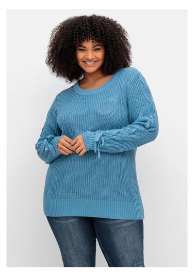 Вязаный свитер с плетеными лентами на рукавах.