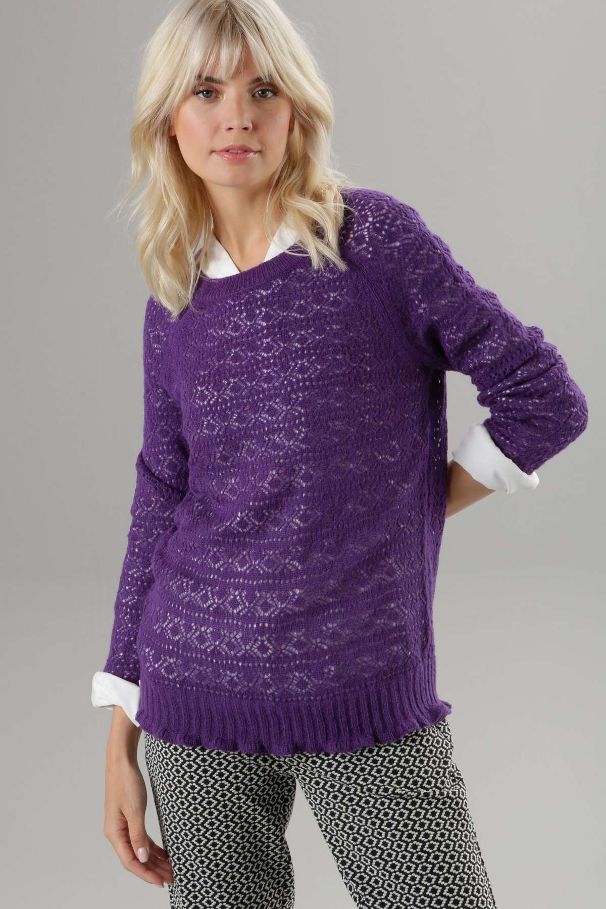 Вязаный свитер ажурным узором и волнистым краем.